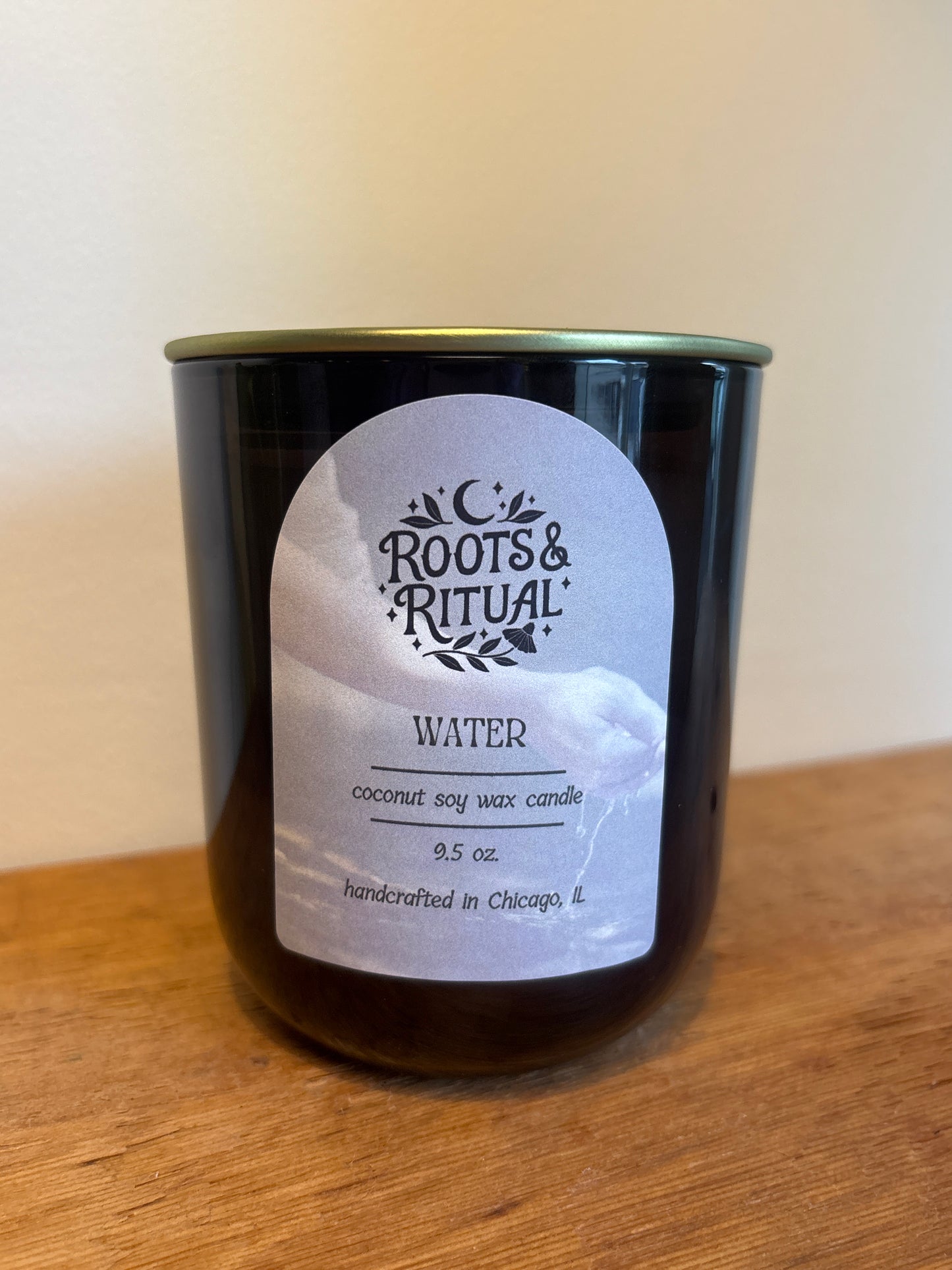 Candle in a black container with a label on a wooden surface