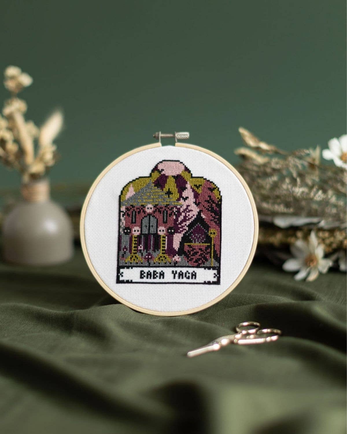 Embroidery hoop with Baba Yaga design on a green fabric background