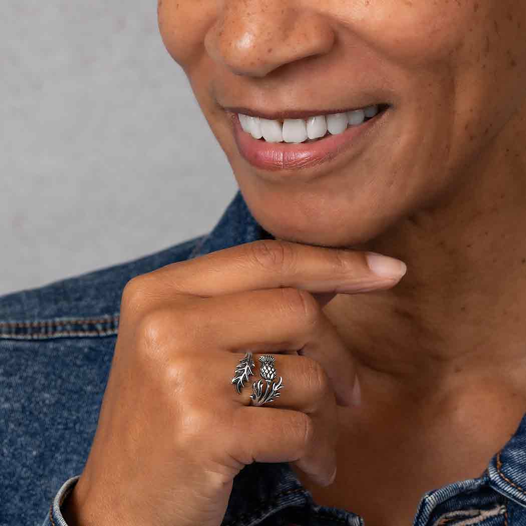 Person wearing a silver ring with a leaf design on a gray background
