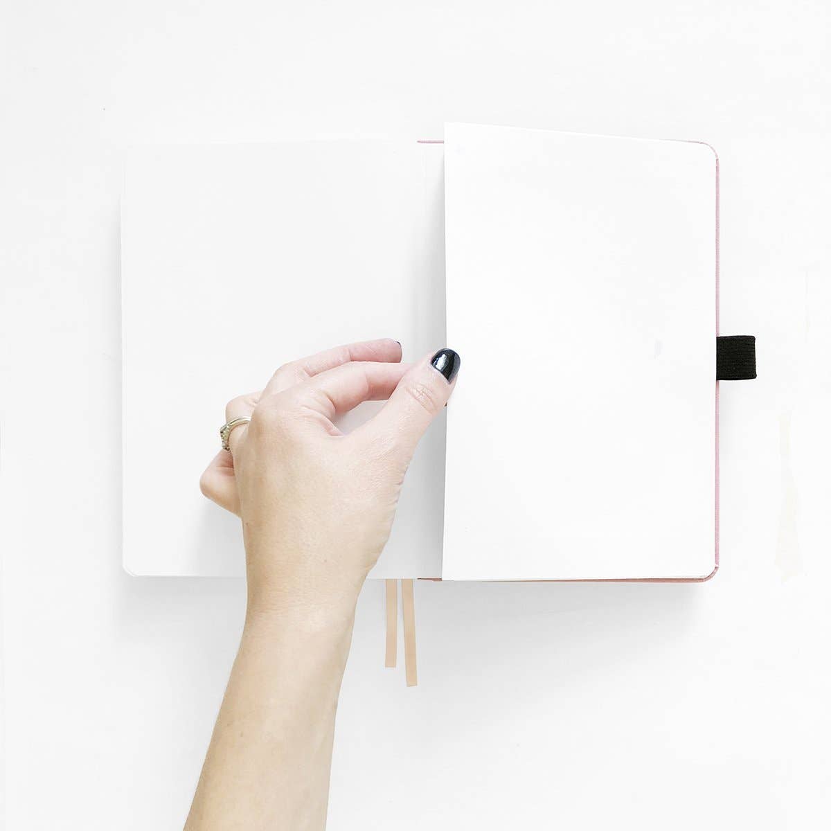 Hand opening a notebook on a white background
