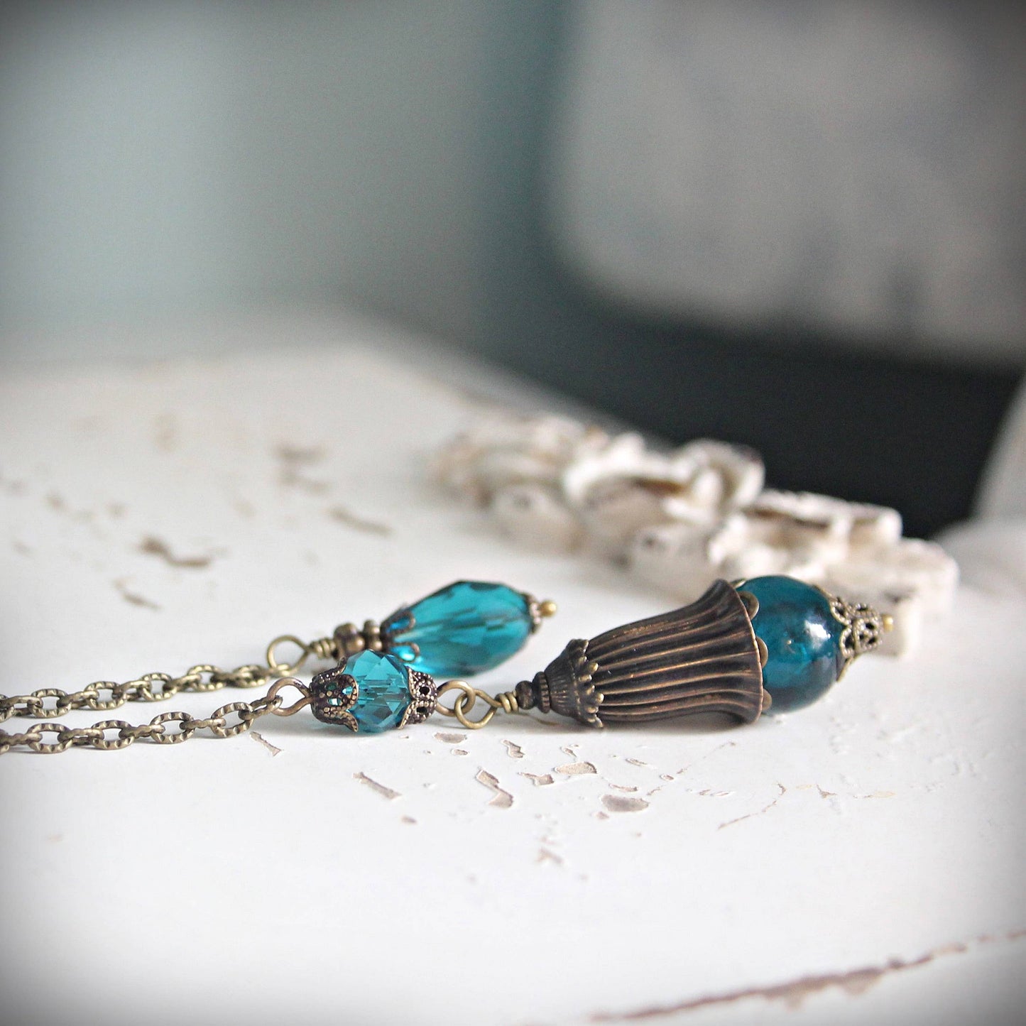 Pendulum with blue beads and a decorative clasp on a marble surface
