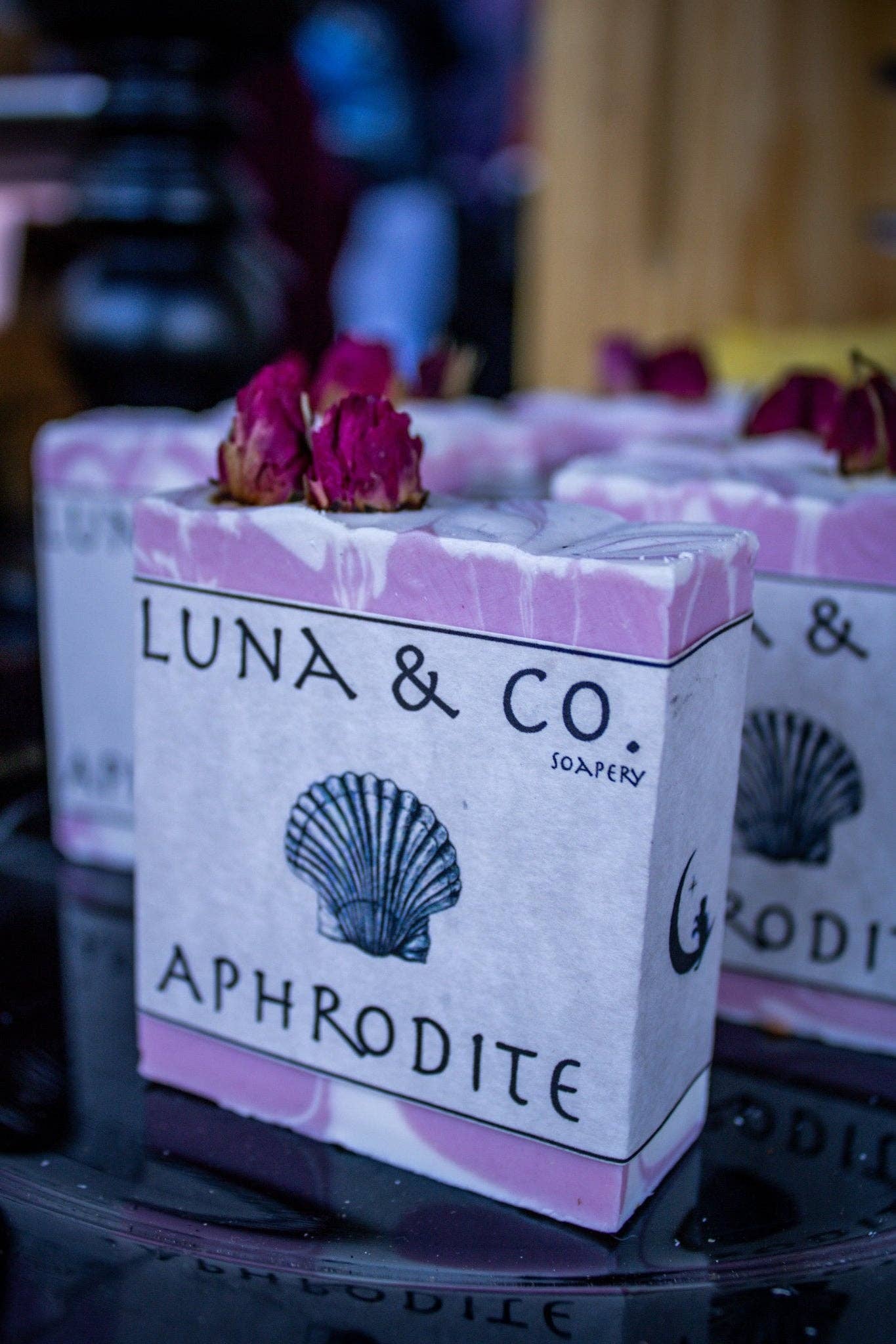 Soap bar with 'Luna & Co.' branding and decorative elements on a reflective surface.