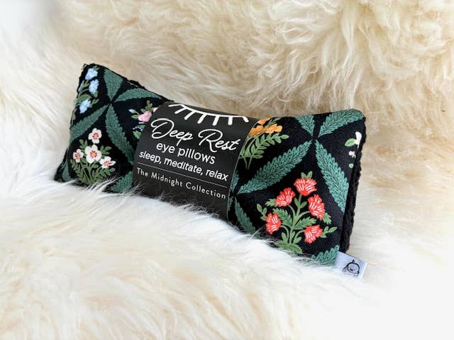 Decorative eye pillow with floral patterns on a fluffy white surface