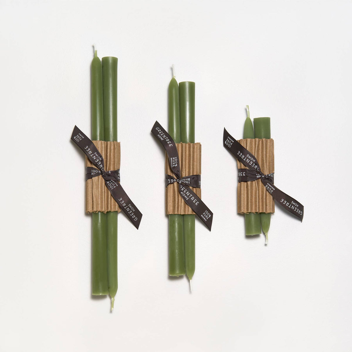 Three pairs of green candles wrapped in brown paper and black ribbons on a white background