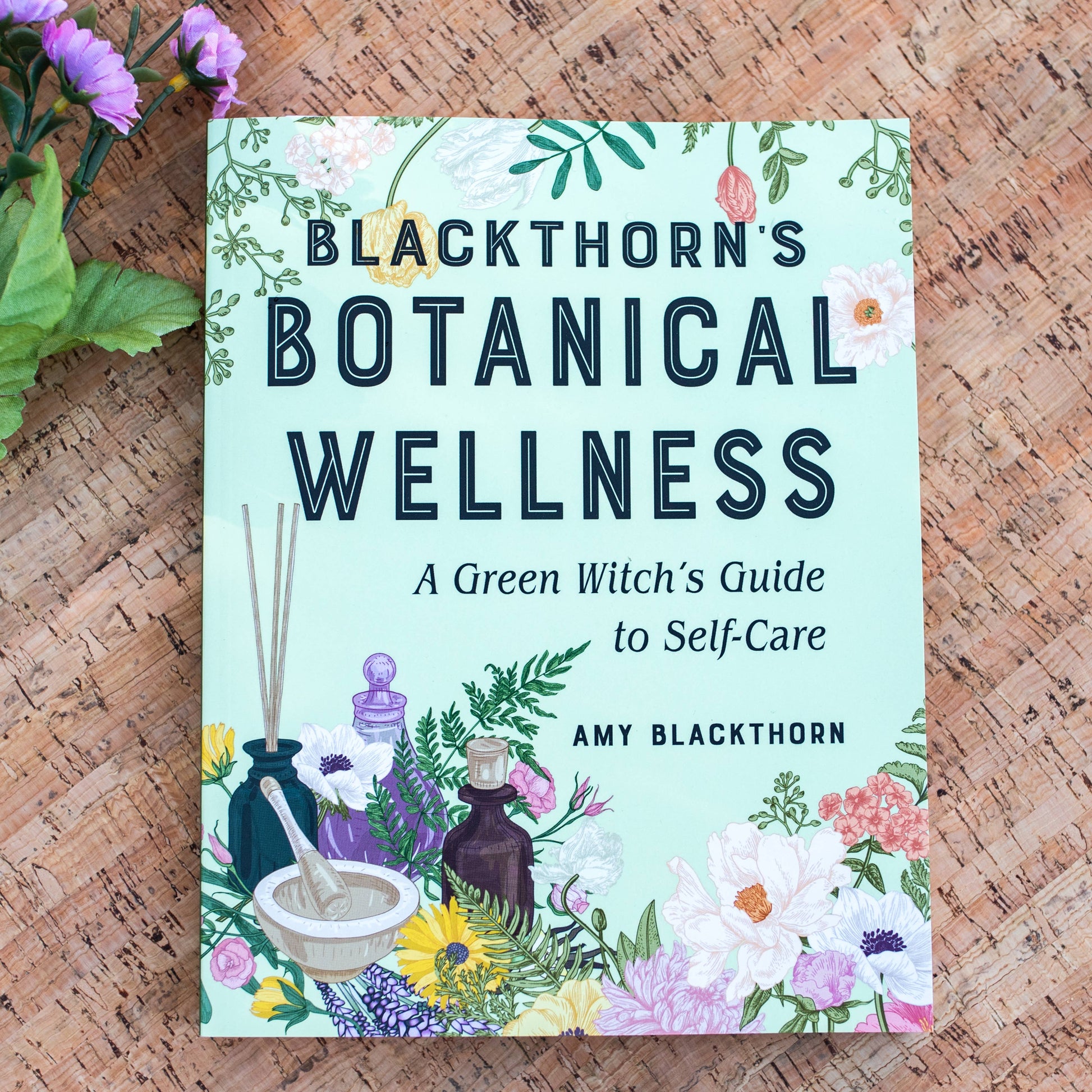 Book titled 'Blackthorn's Botanical Wellness' on a wooden surface with floral elements.