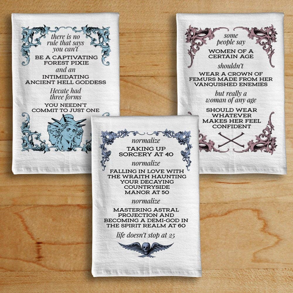 Three decorative towels with text and illustrations on a wooden surface