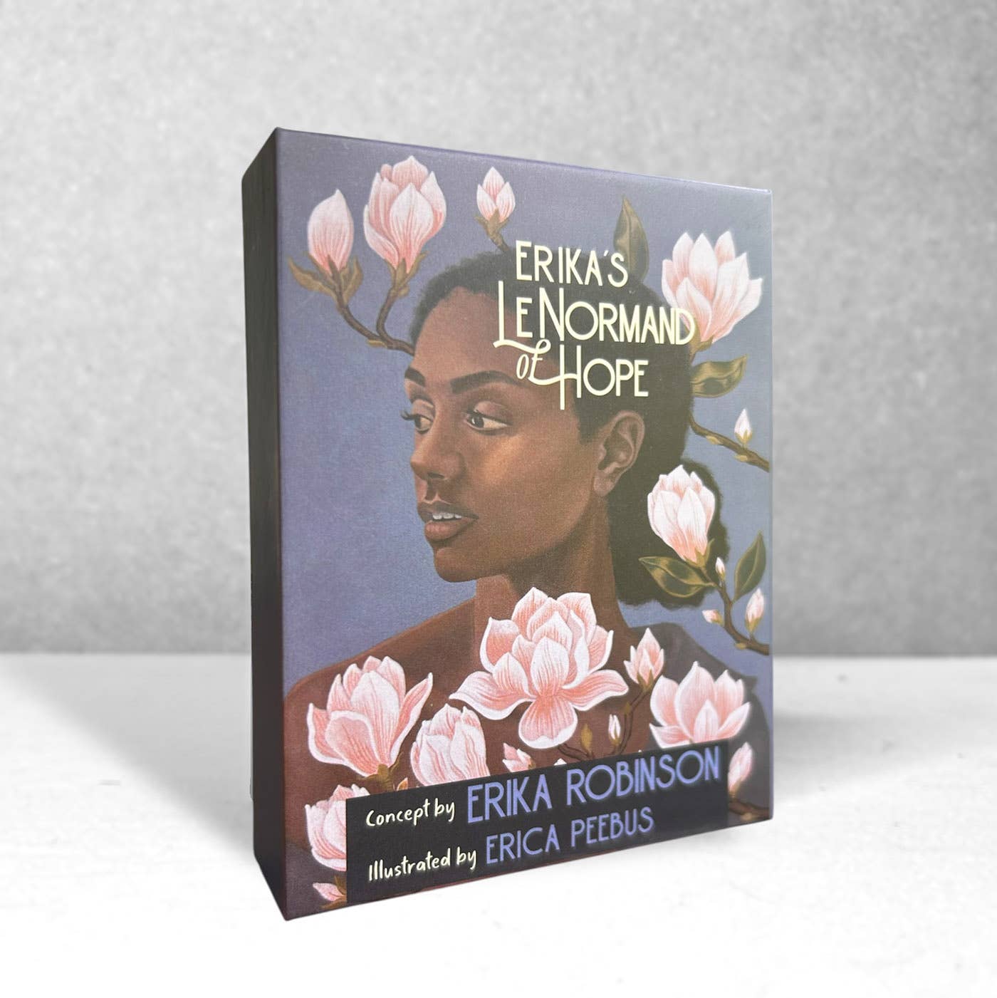Oracle card box with illustration of a woman's face surrounded by flowers on a gray background