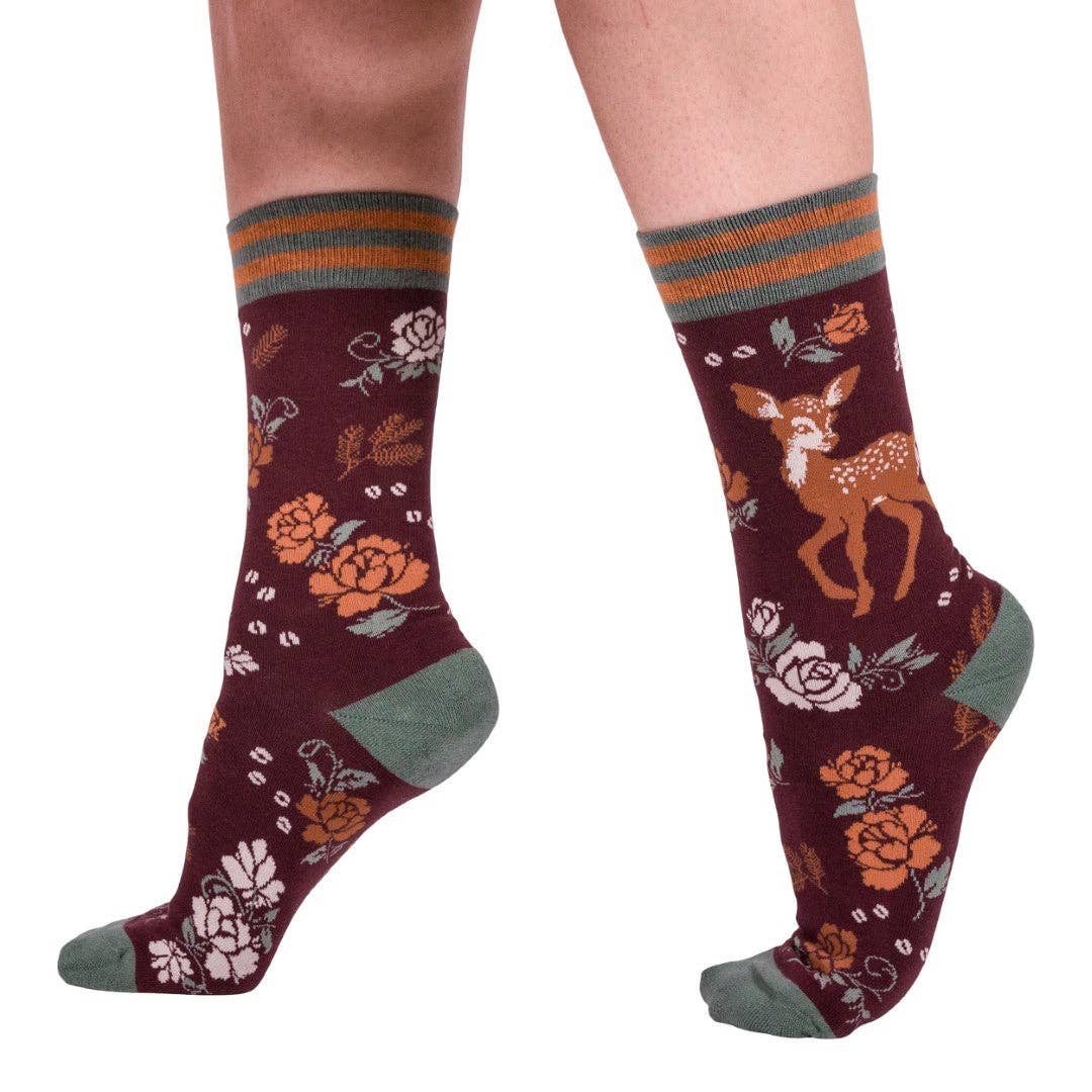 Maroon socks with deer and floral patterns worn by a person on a white background