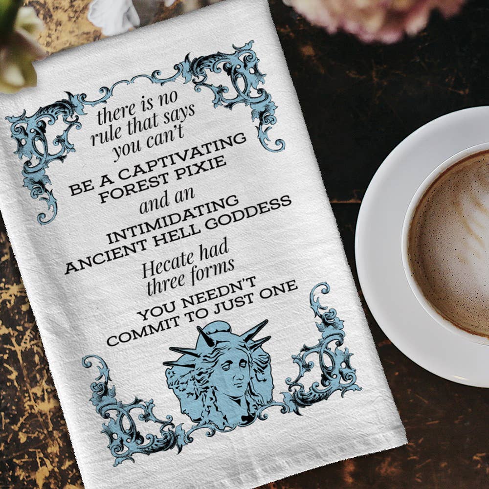 Tea towel with decorative text and illustrations on a wooden surface with a cup of coffee.