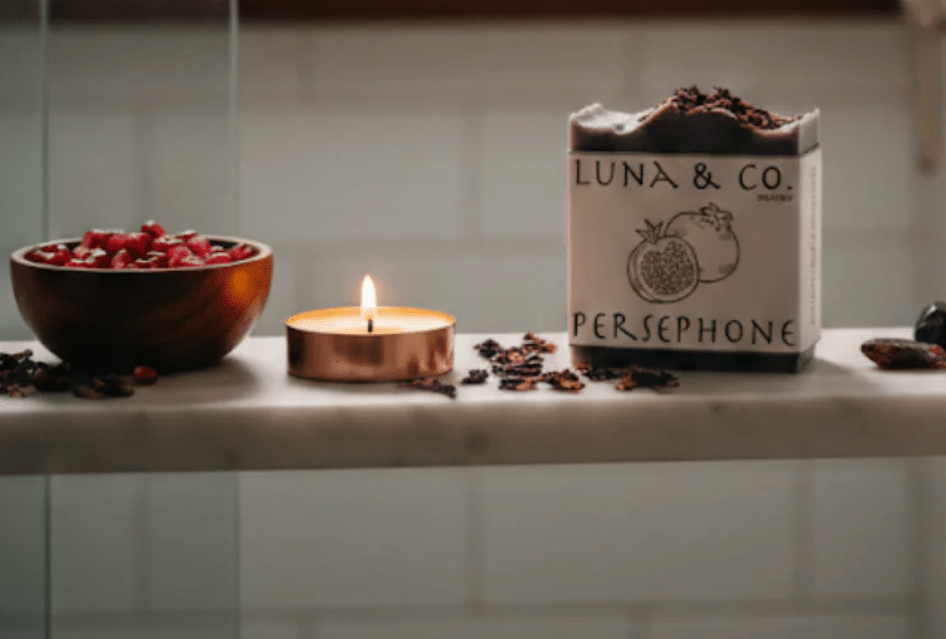 Luna & Co. soap bar with a lit candle and decorative items on a surface.