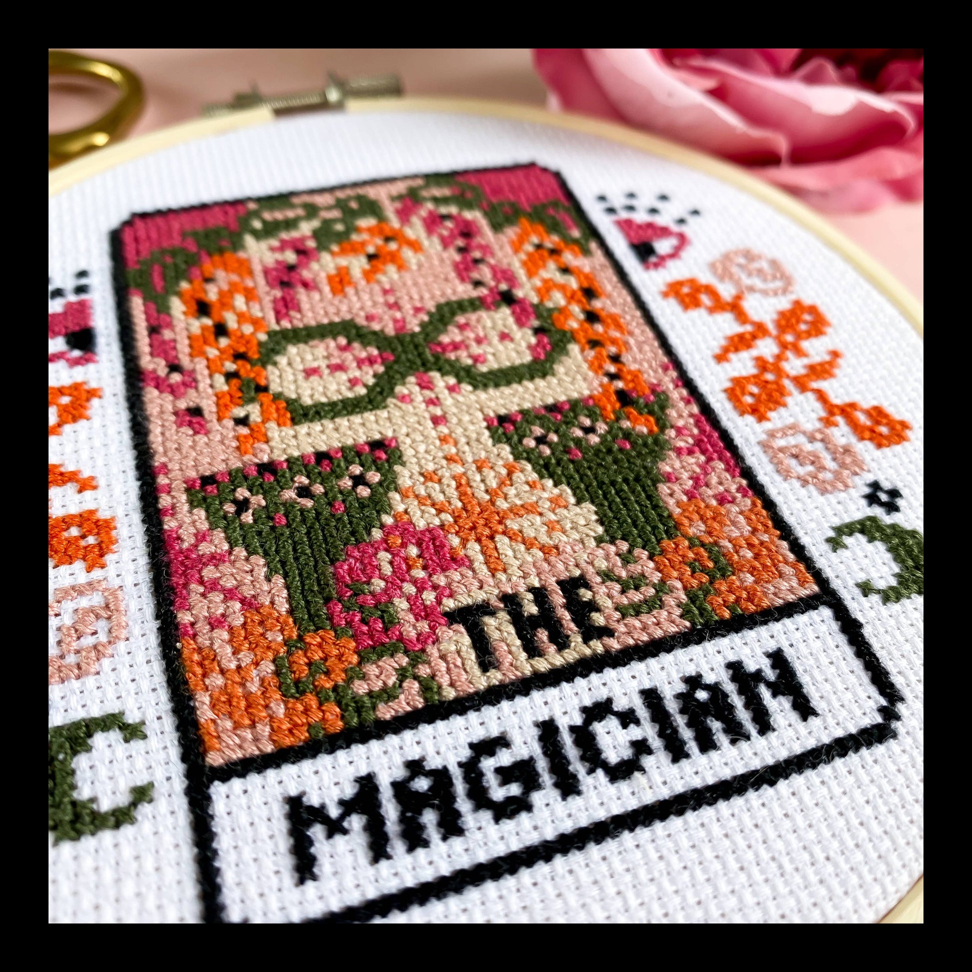 Cross-stitched design of 'The Magician' from Tarot cards in an embroidery hoop.