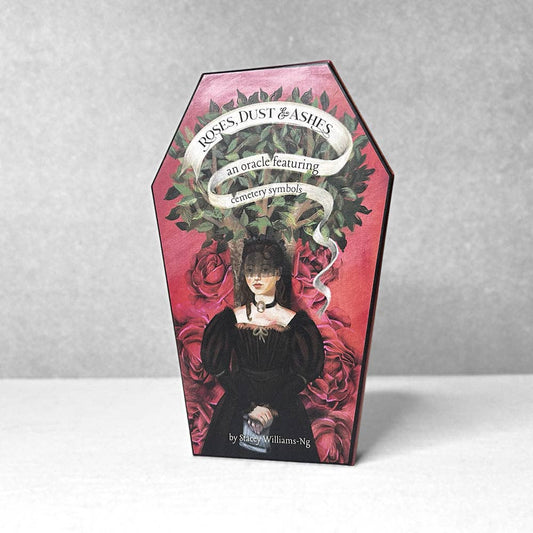 Ornate packaging for 'Roses, Dust & Ashes' oracle cards with a woman's face and floral design.
