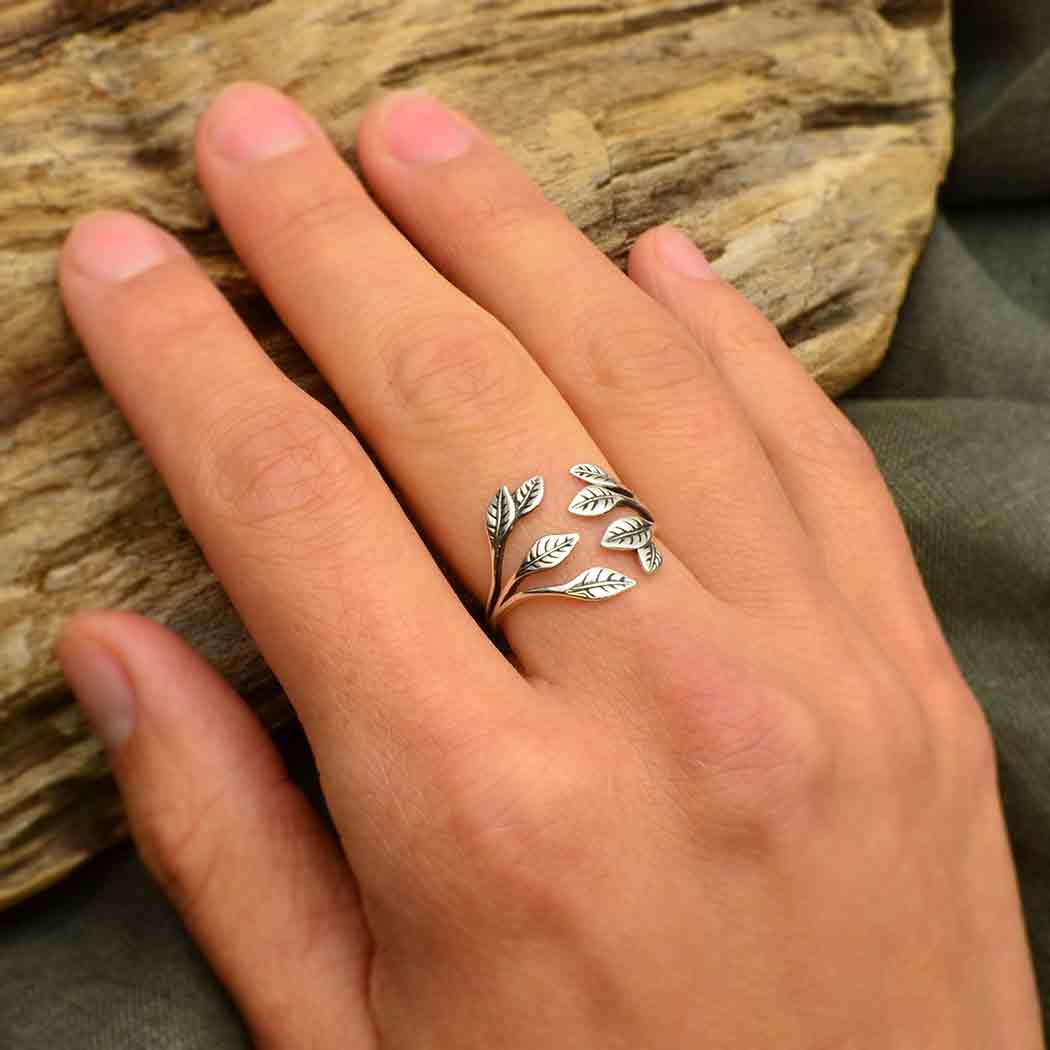 Silver leaf ring on a hand with a wooden background