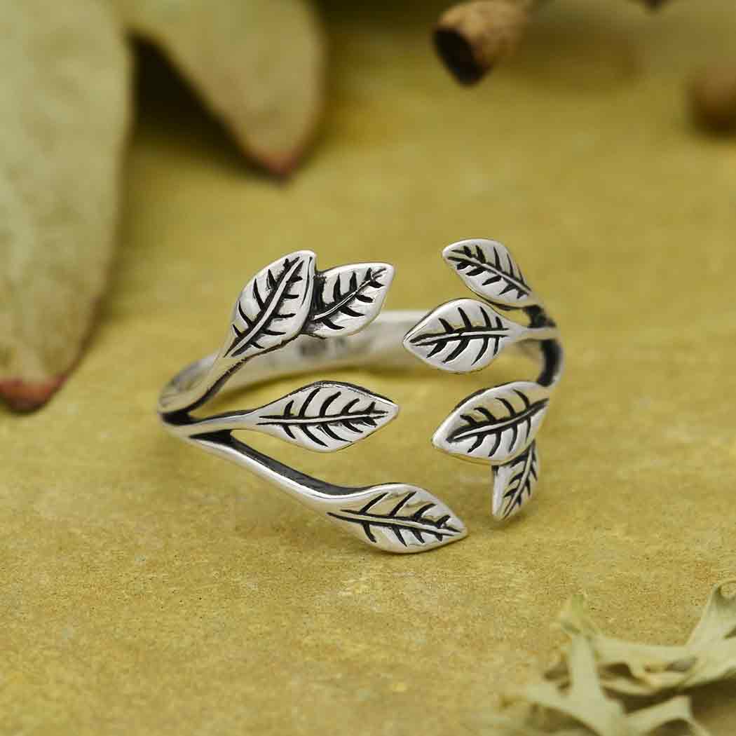 Silver leaf-shaped ring on a textured beige surface
