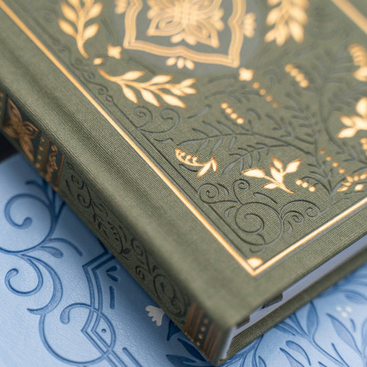 Green book with gold embossed design on a blue patterned surface