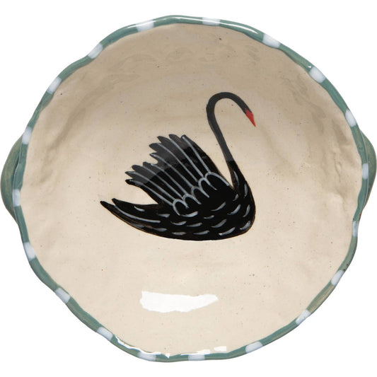 A round ceramic bowl with a scalloped rim, featuring a black swan illustration in the center and a green and white patterned edge.