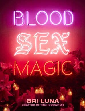 Neon sign with 'Blood Sex Magic' text and Bri Luna's name on a dark background with candles and flowers.