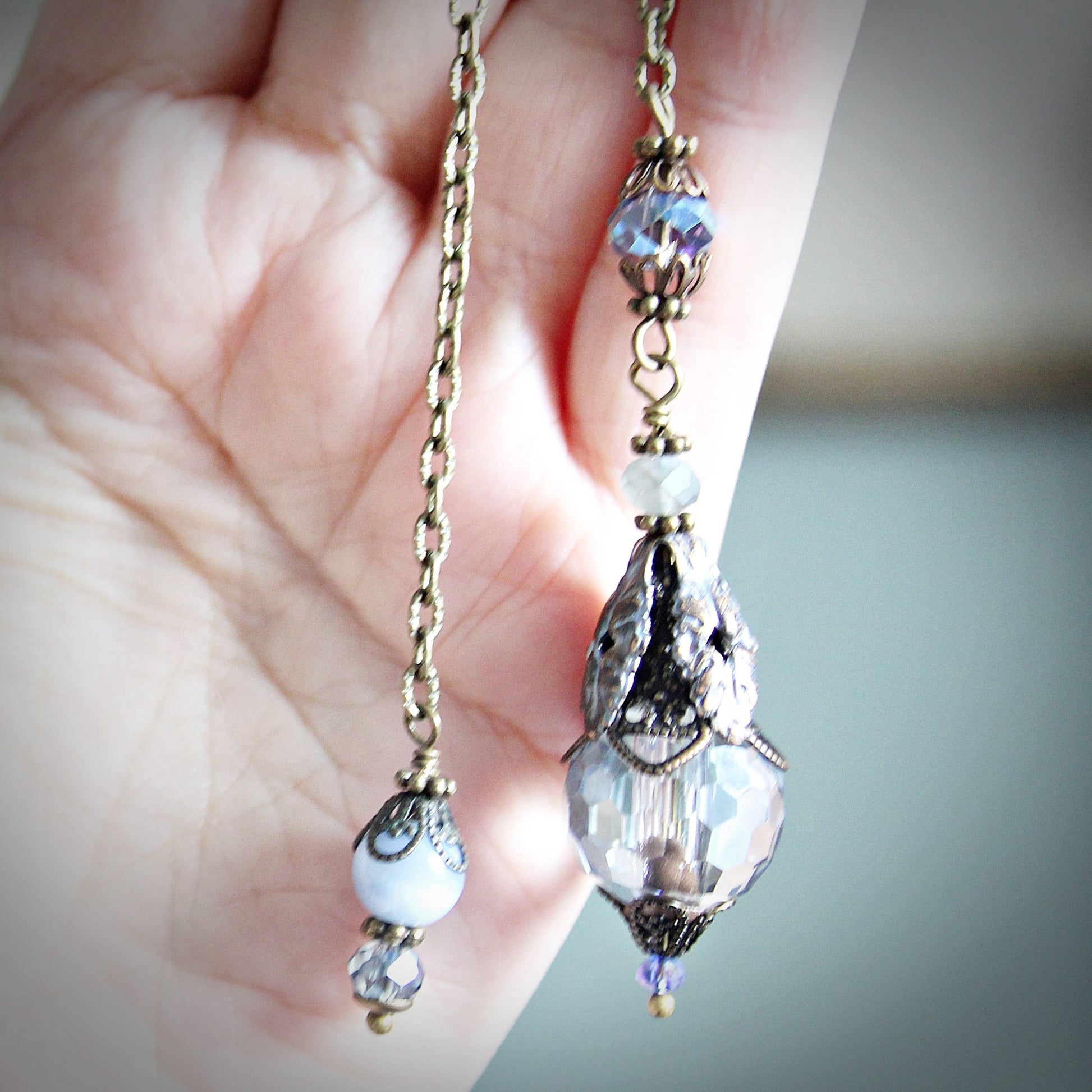 Delicate beaded earrings held in a hand with a blurred background