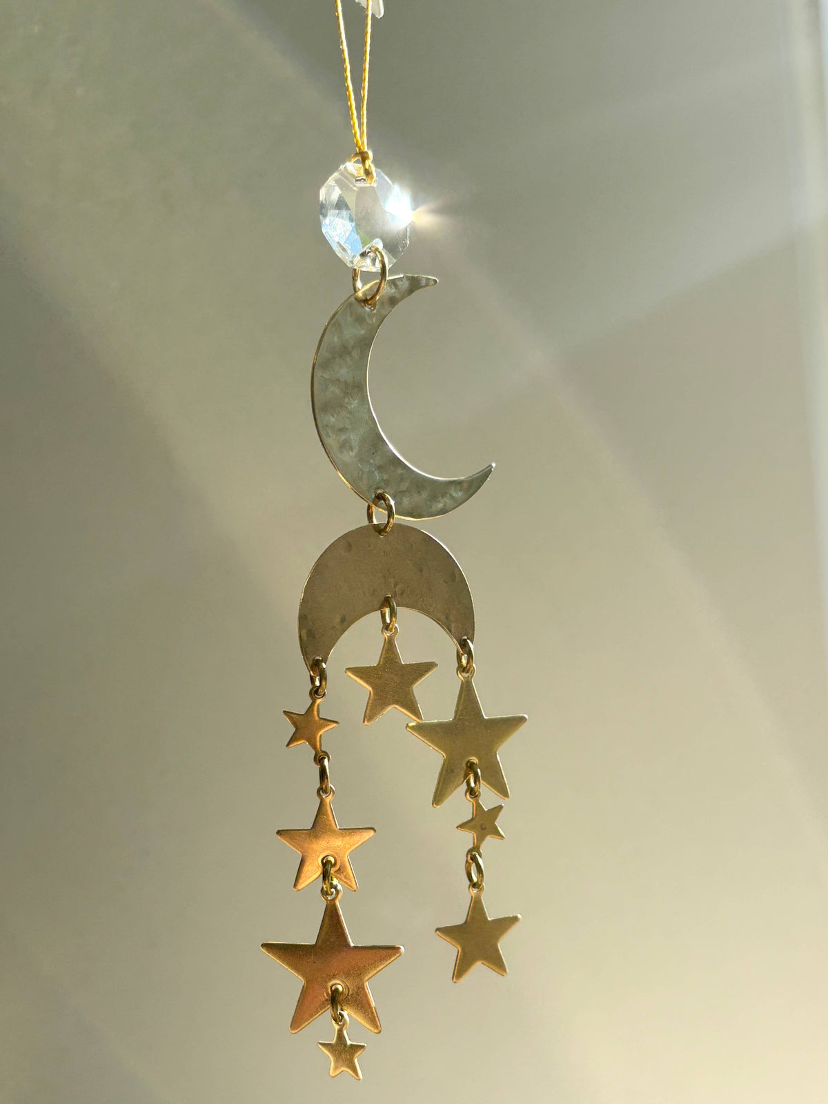 Decorative hanging ornament with a moon and stars design on a neutral background