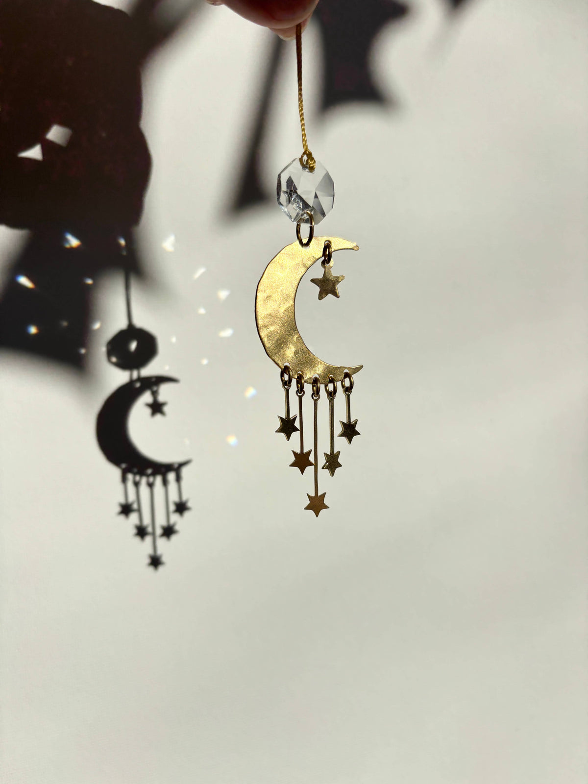 Gold crescent moon and star earrings with dangling stars on a light gray background.