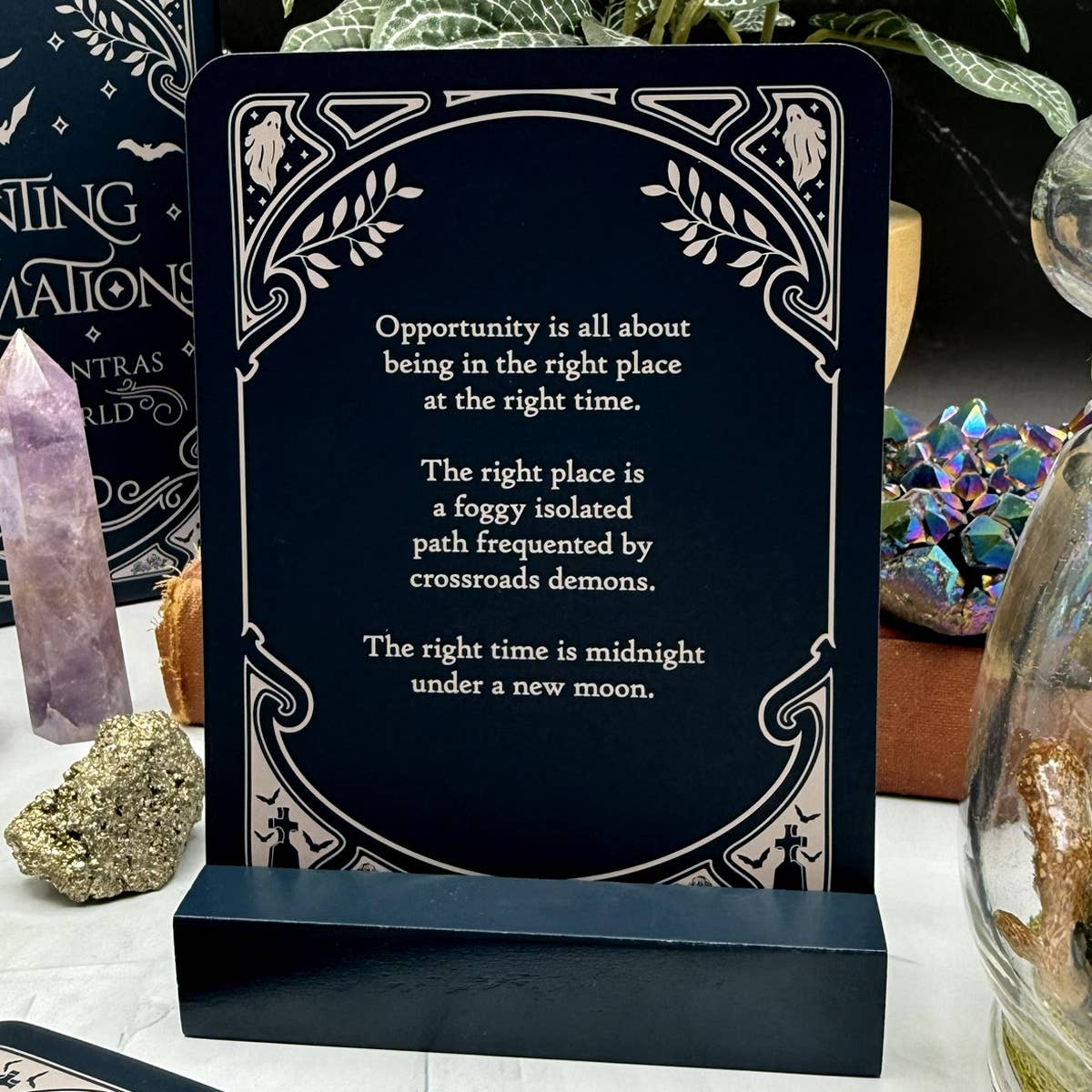Decorative card with motivational quote on a stand, surrounded by mystical items.