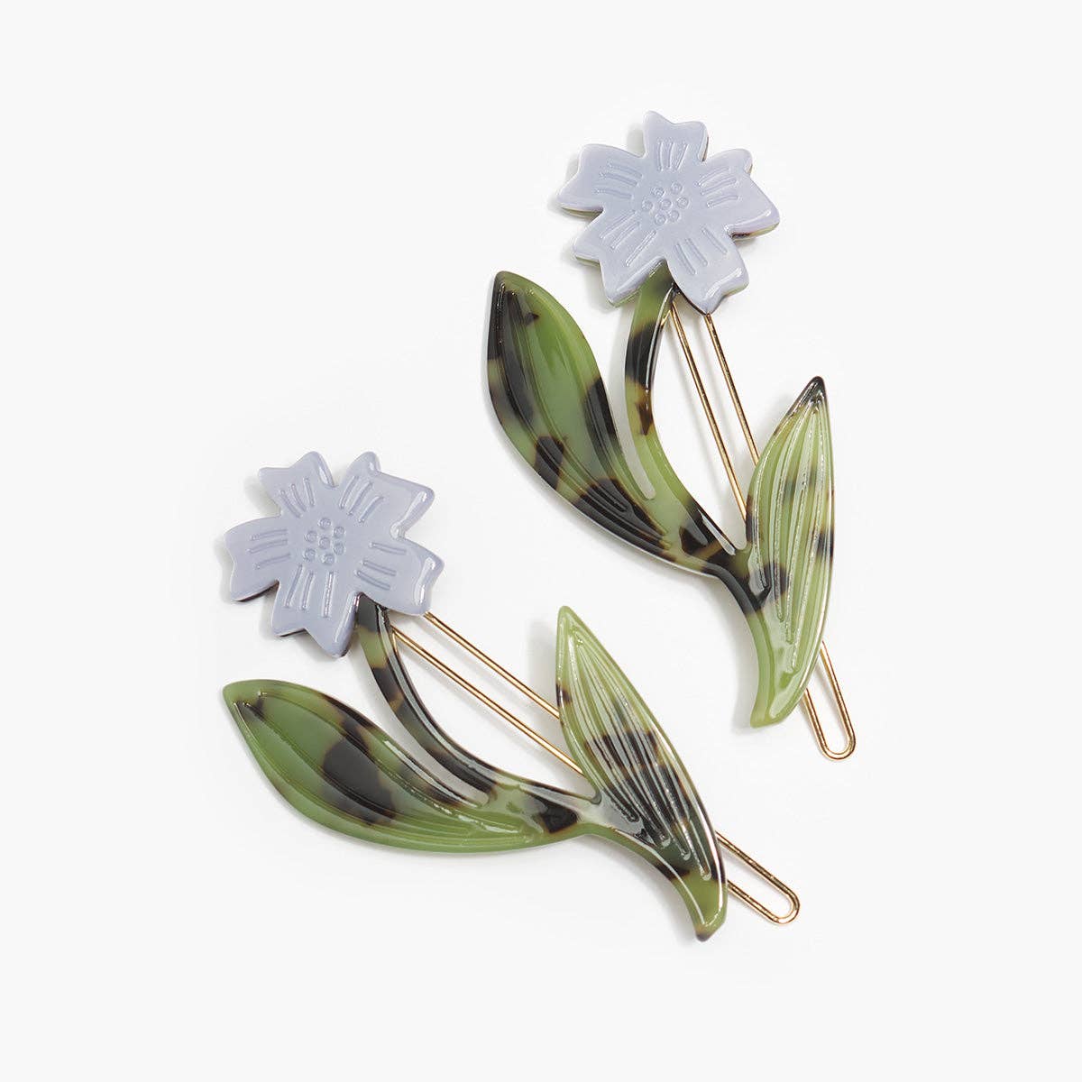Two flower-shaped hair clips with glossy green and black marbled leaves and pale lavender-white petals, displayed on a clean white background.