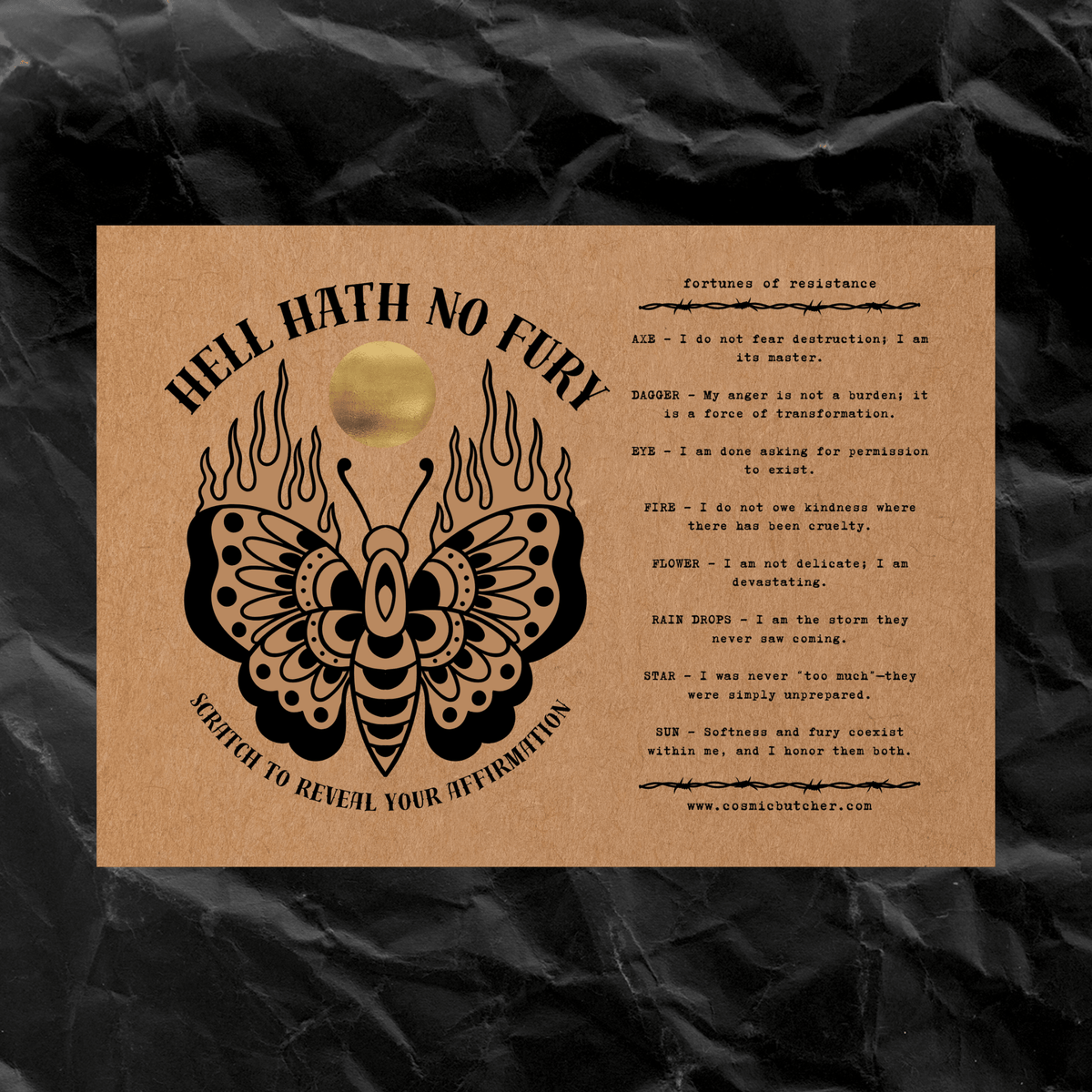 A square kraft paper card with black printed occult-style text and a butterfly/flame graphic, placed on a dark crumpled paper background. The card includes a small circular gold-toned element near the top center.