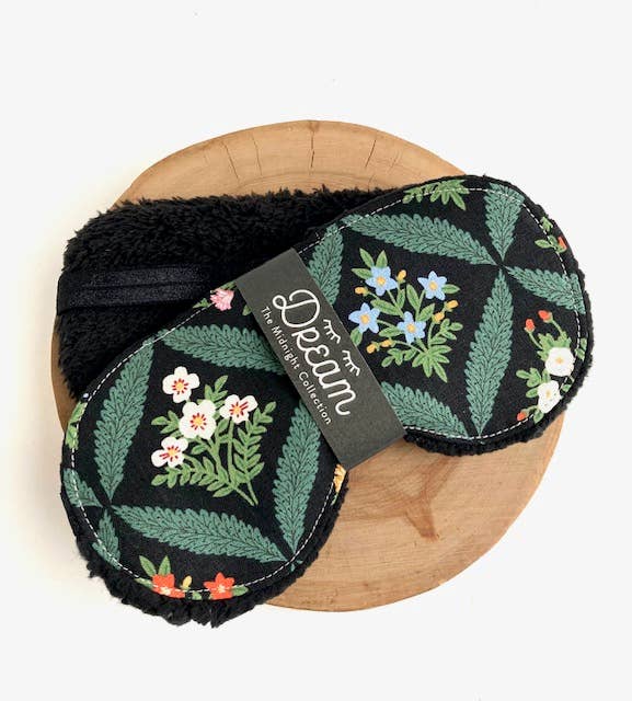 Floral patterned eye mask on a wooden board with a brand tag.