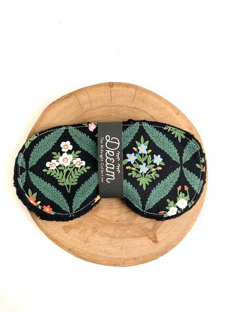 Floral patterned eye mask on a wooden board with a white background