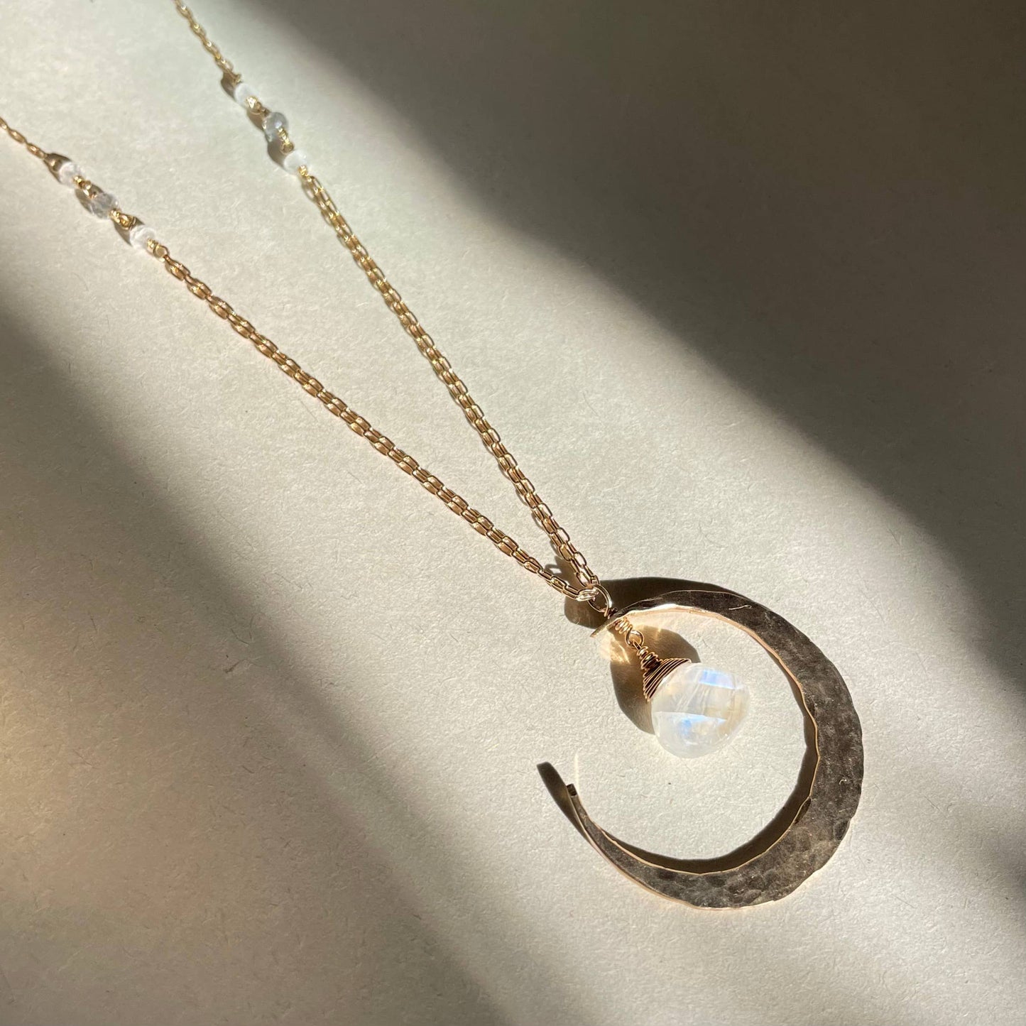 Sterling silver and moonstone crescent moon necklace on a light background.