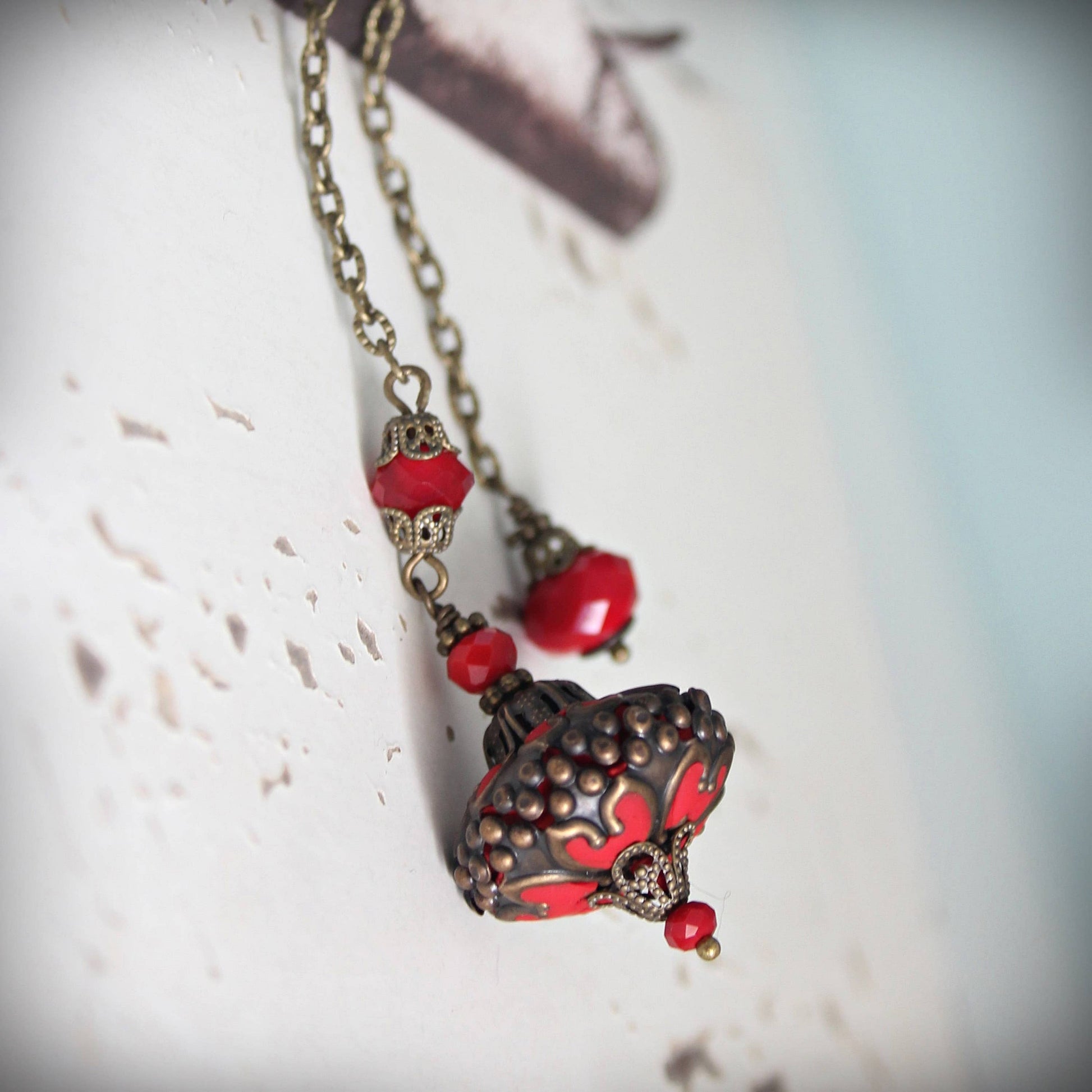 Pendulum with red and gold pendant on a textured surface