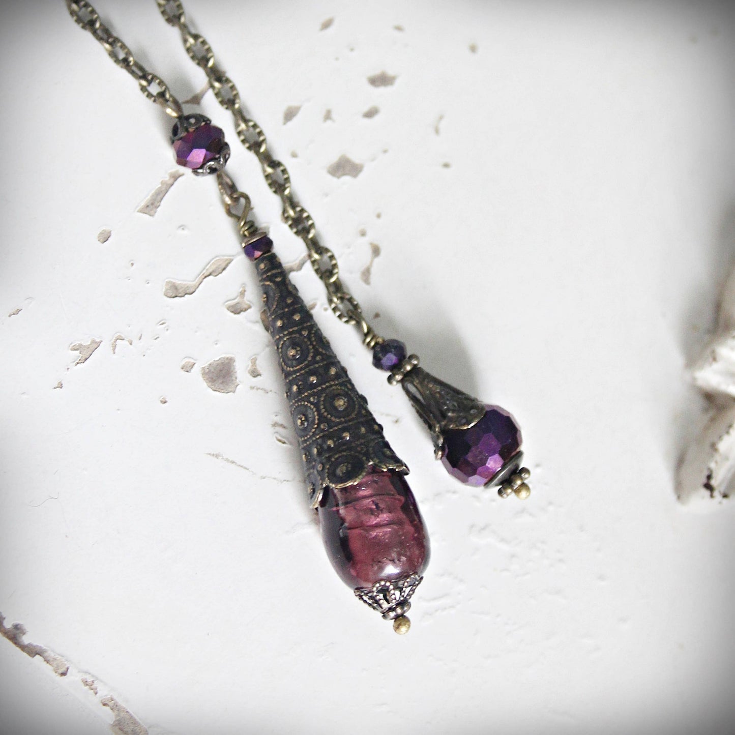 Pendulum with purple beads on a textured white surface