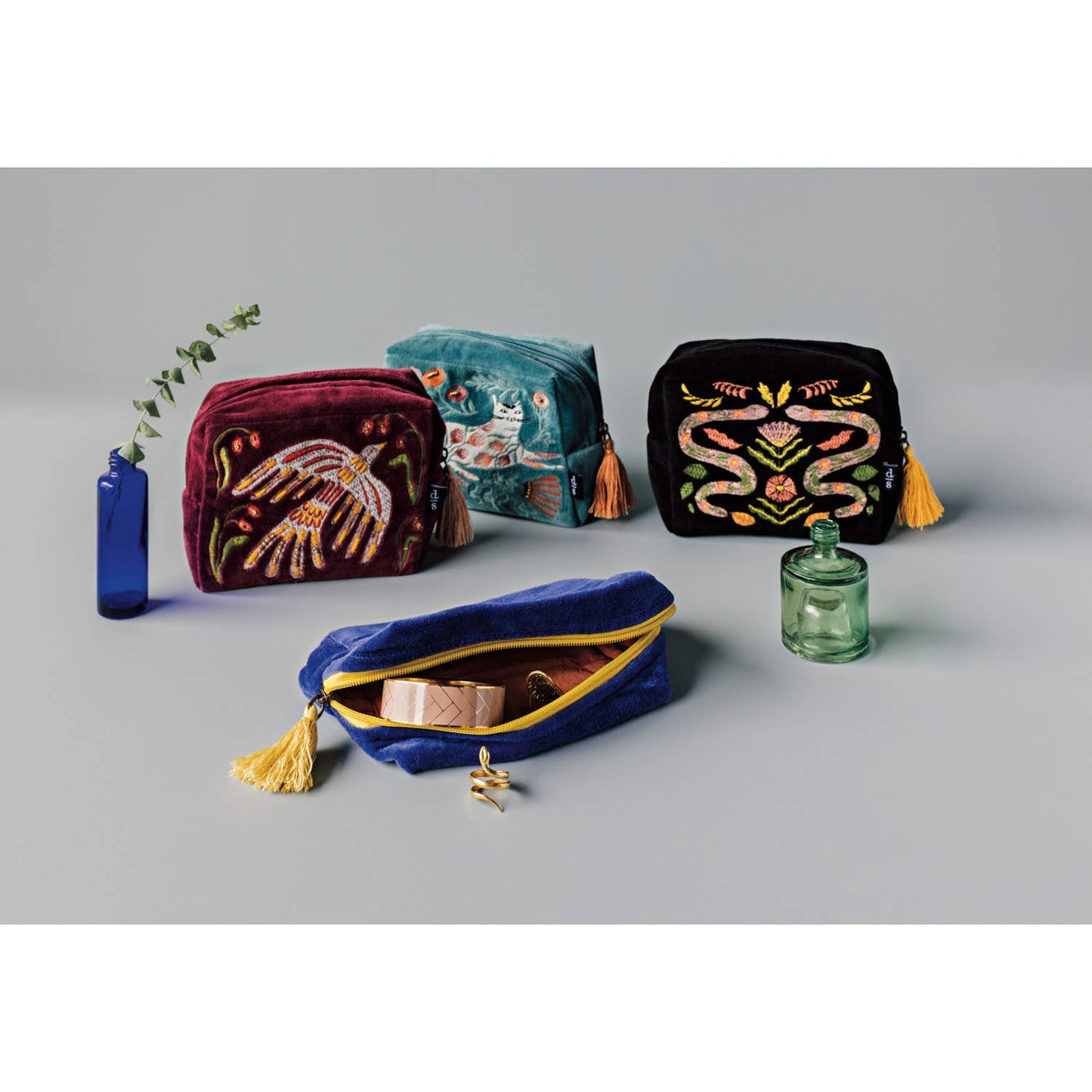 Set of colorful embroidered bags and bottles on a gray background
