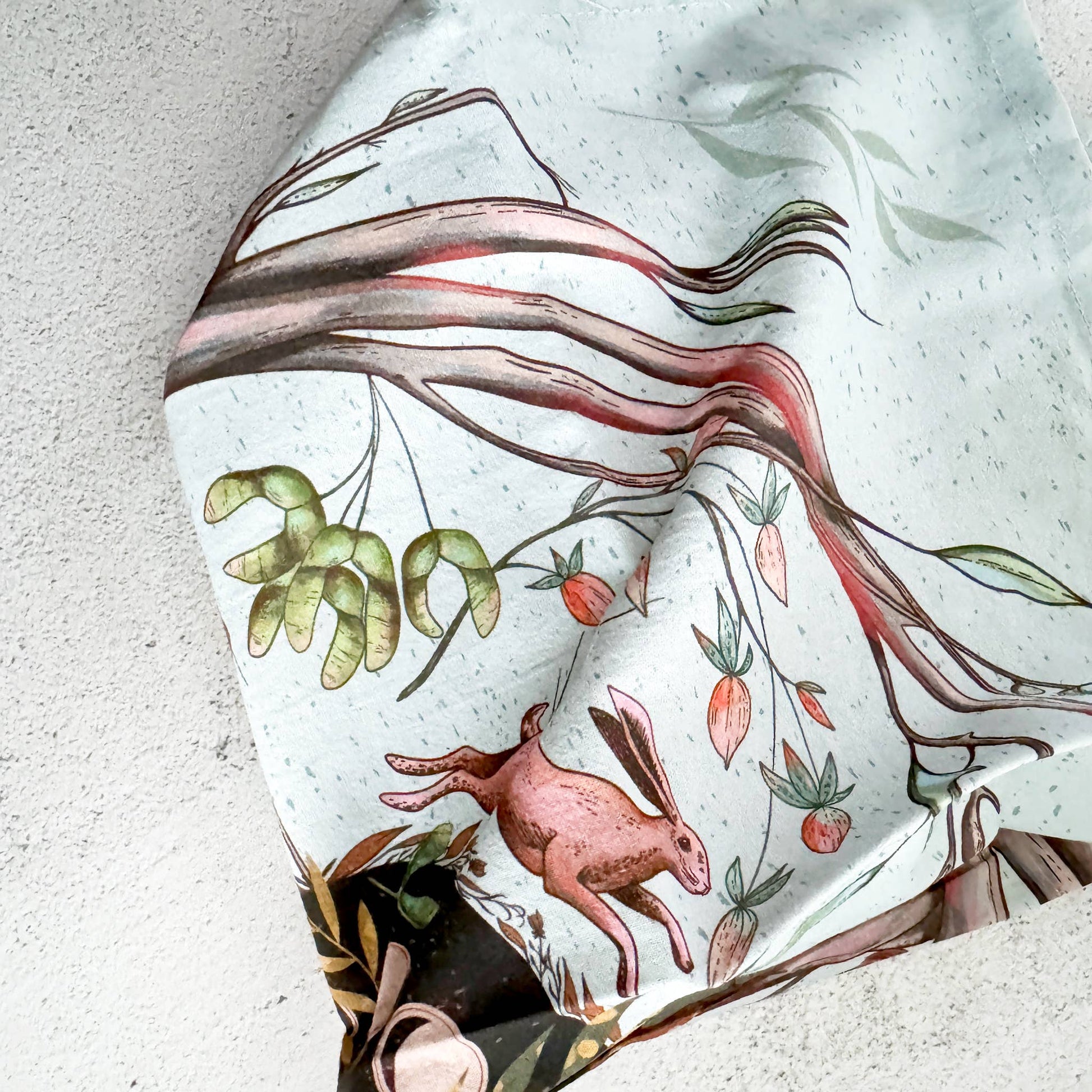 Decorative cloth with a rabbit and leaf design on a textured surface