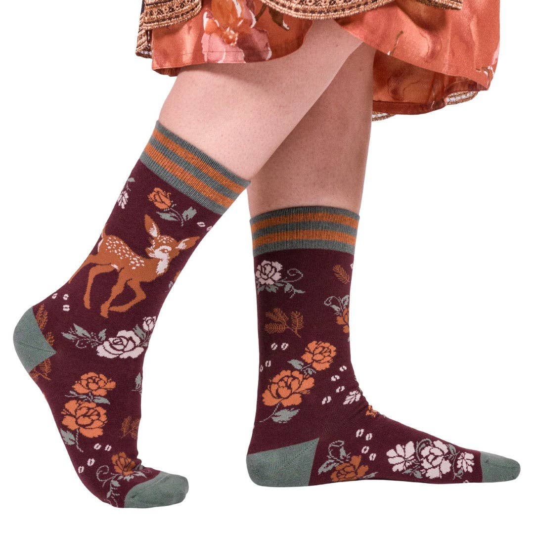 Knee-high socks with deer and floral design worn by a person on a white background