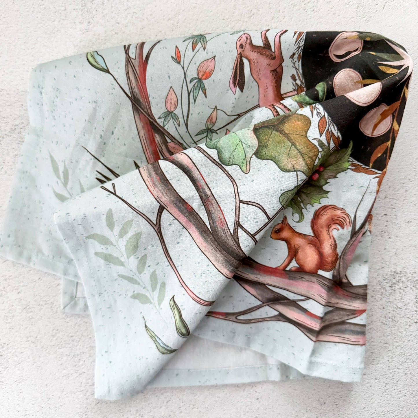 Set of fabric rolls with nature-themed designs featuring animals and plants on a textured surface.