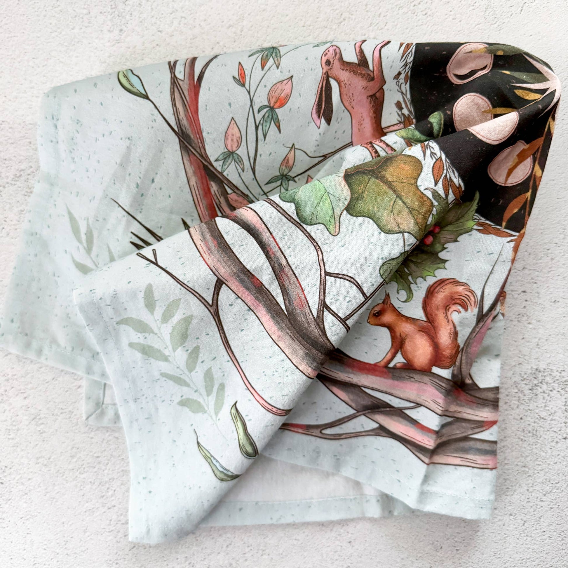 Set of fabric rolls with nature-themed designs featuring animals and plants on a textured surface.