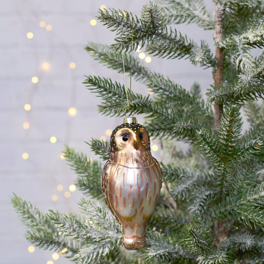 Decorative owl ornament hanging on a Christmas tree with a soft light background