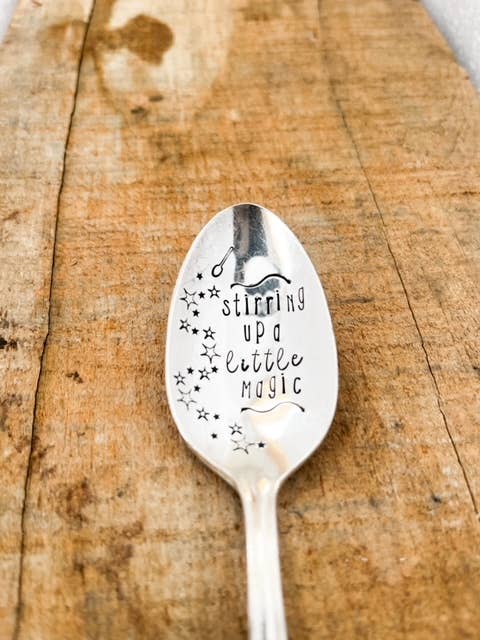 Silver spoon with engraved text on a wooden surface