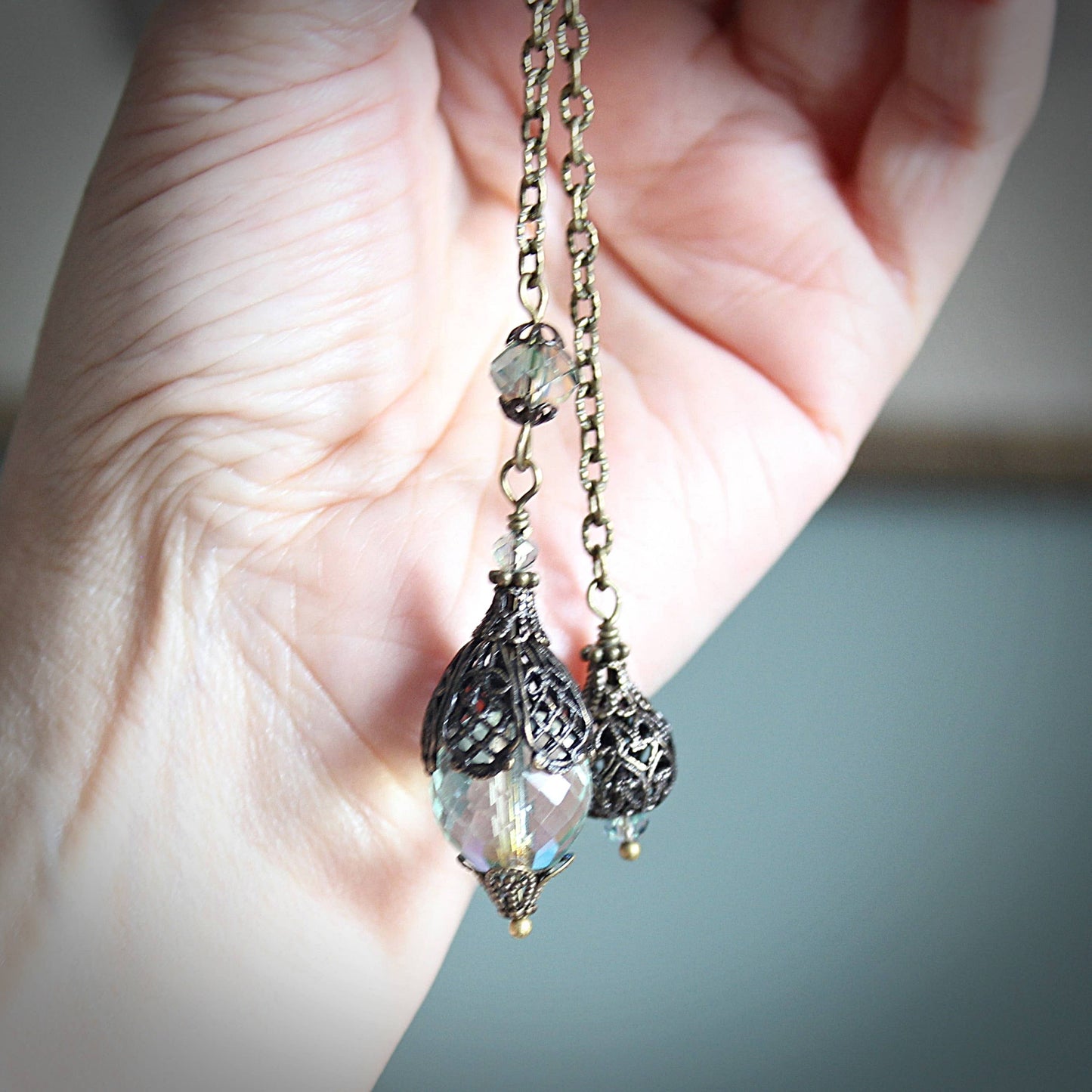 Pendulum with intricate designs held in a hand against a neutral background