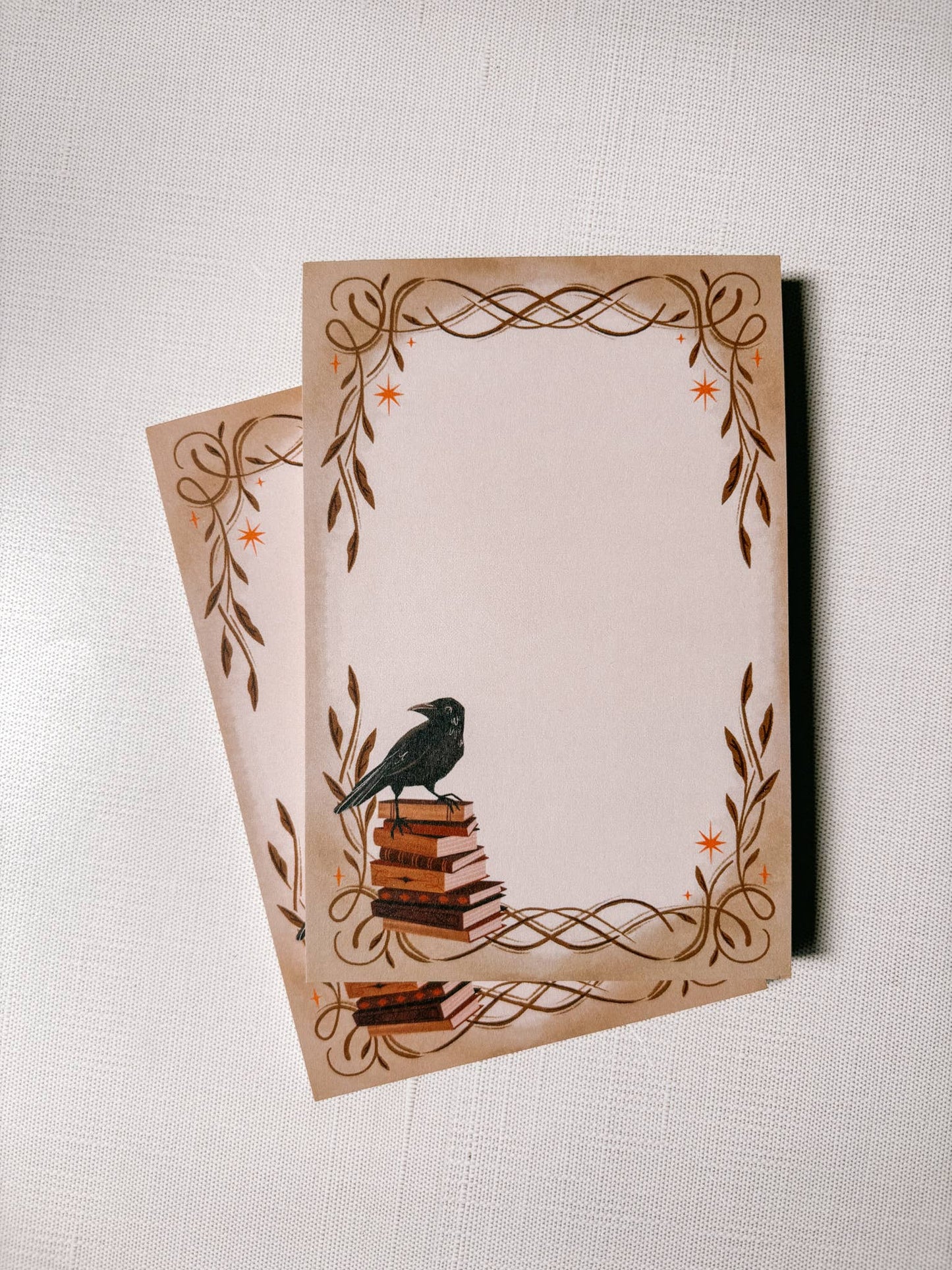 Two decorative notepads with a bird design on a textured surface