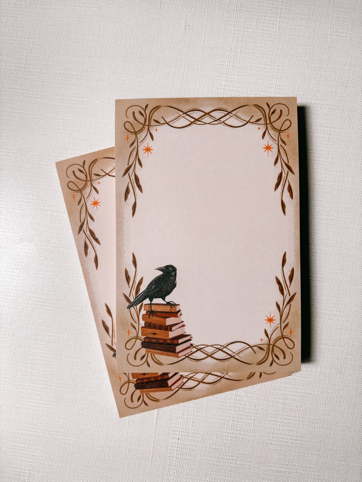 Two decorative notepads with a bird design on a textured surface