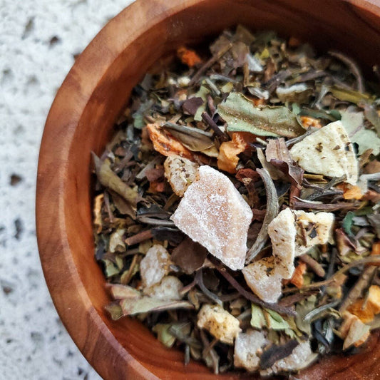 Wooden bowl filled with a mix of dried herbs and spices on a textured surface