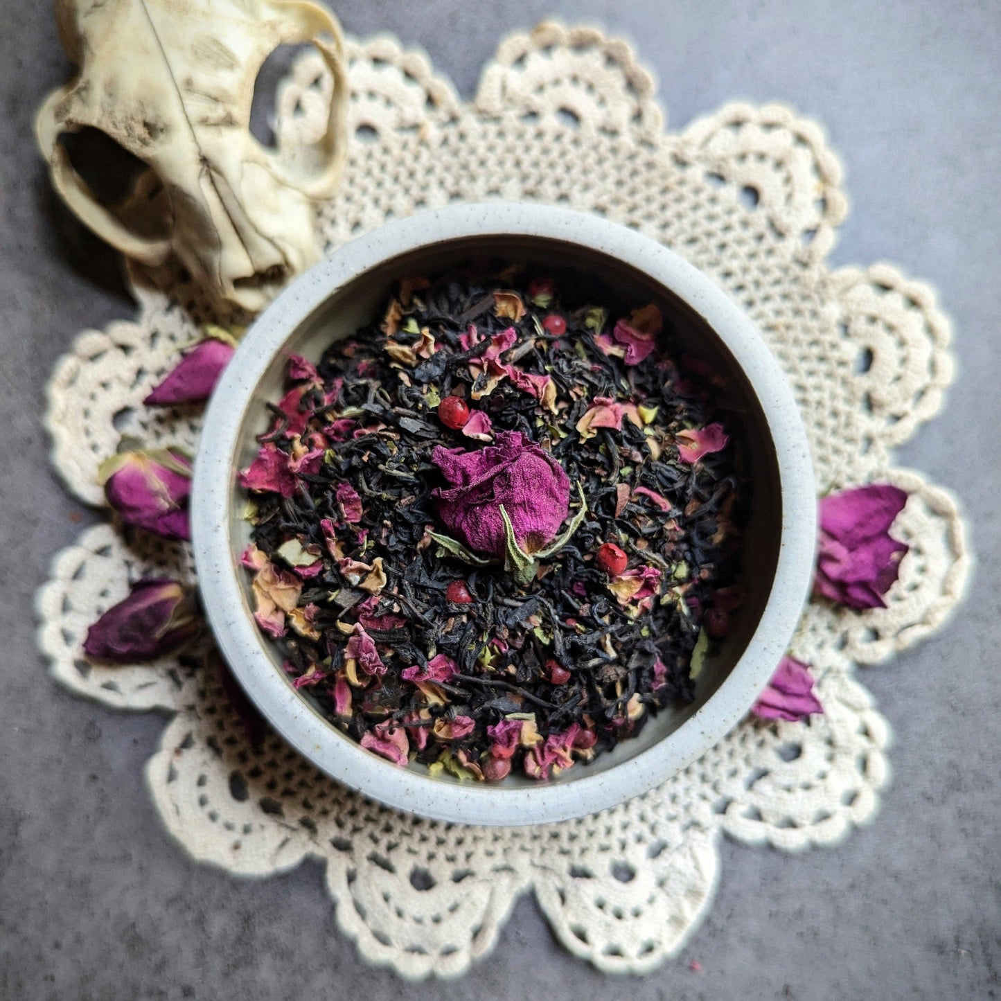 Tea leaves with flowers in a white bowl on a lace doily