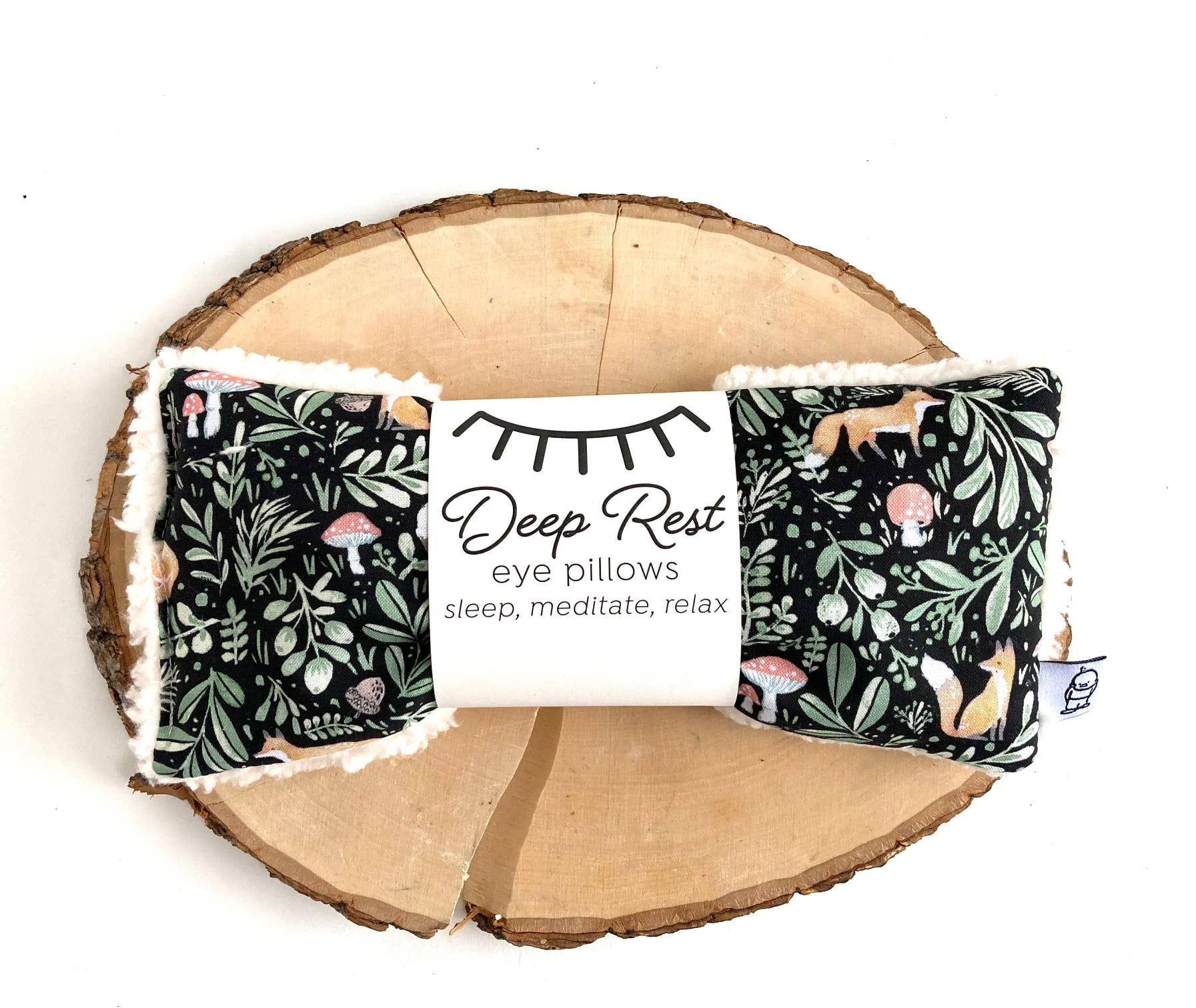 Two eye pillows with a floral pattern on a wooden surface, featuring a 'Deep Rest' label.