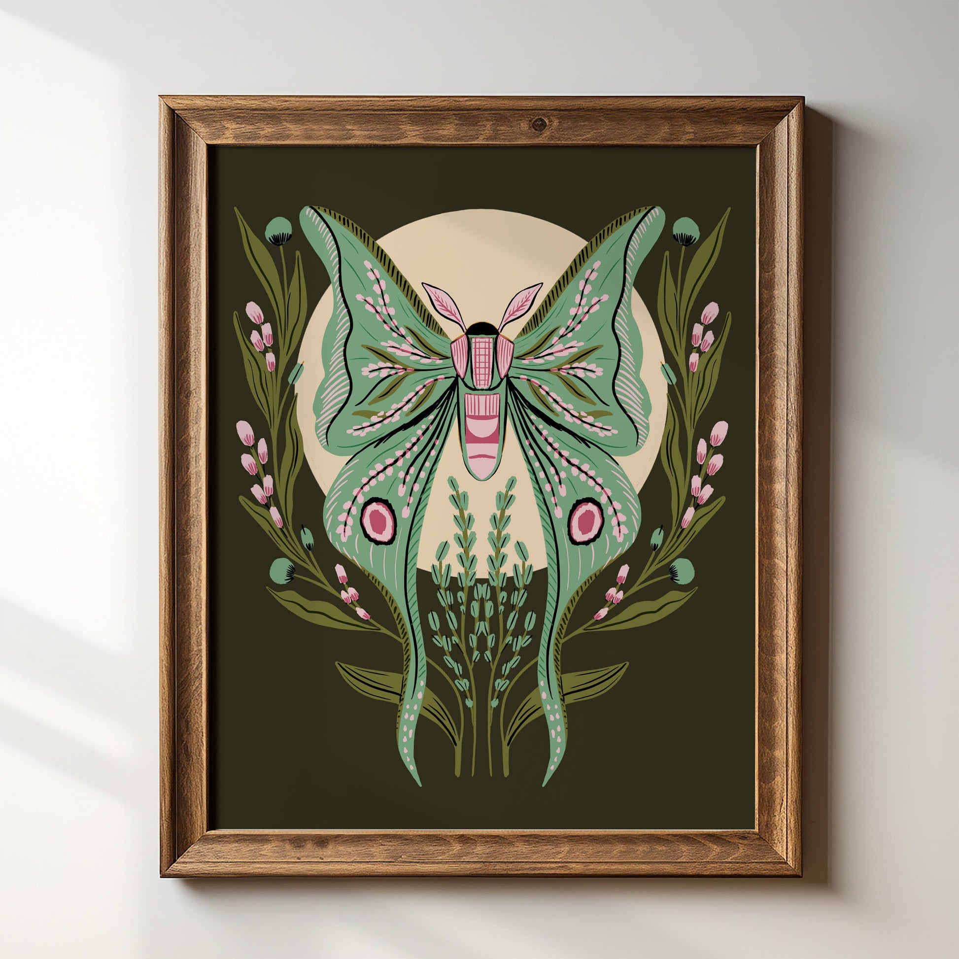 Tara Reed Luna Moth giclee print in a wood frame on a white wall.