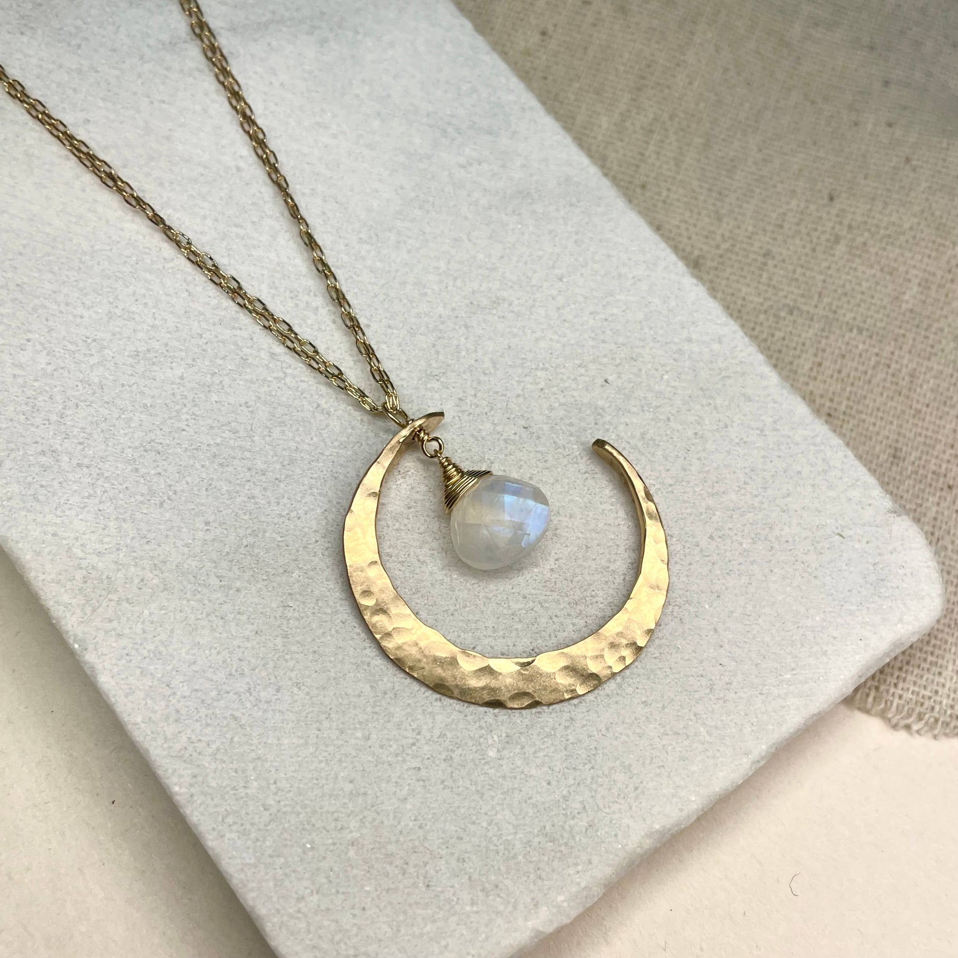 Sterling silver and moonstone crescent moon necklace on a light background.