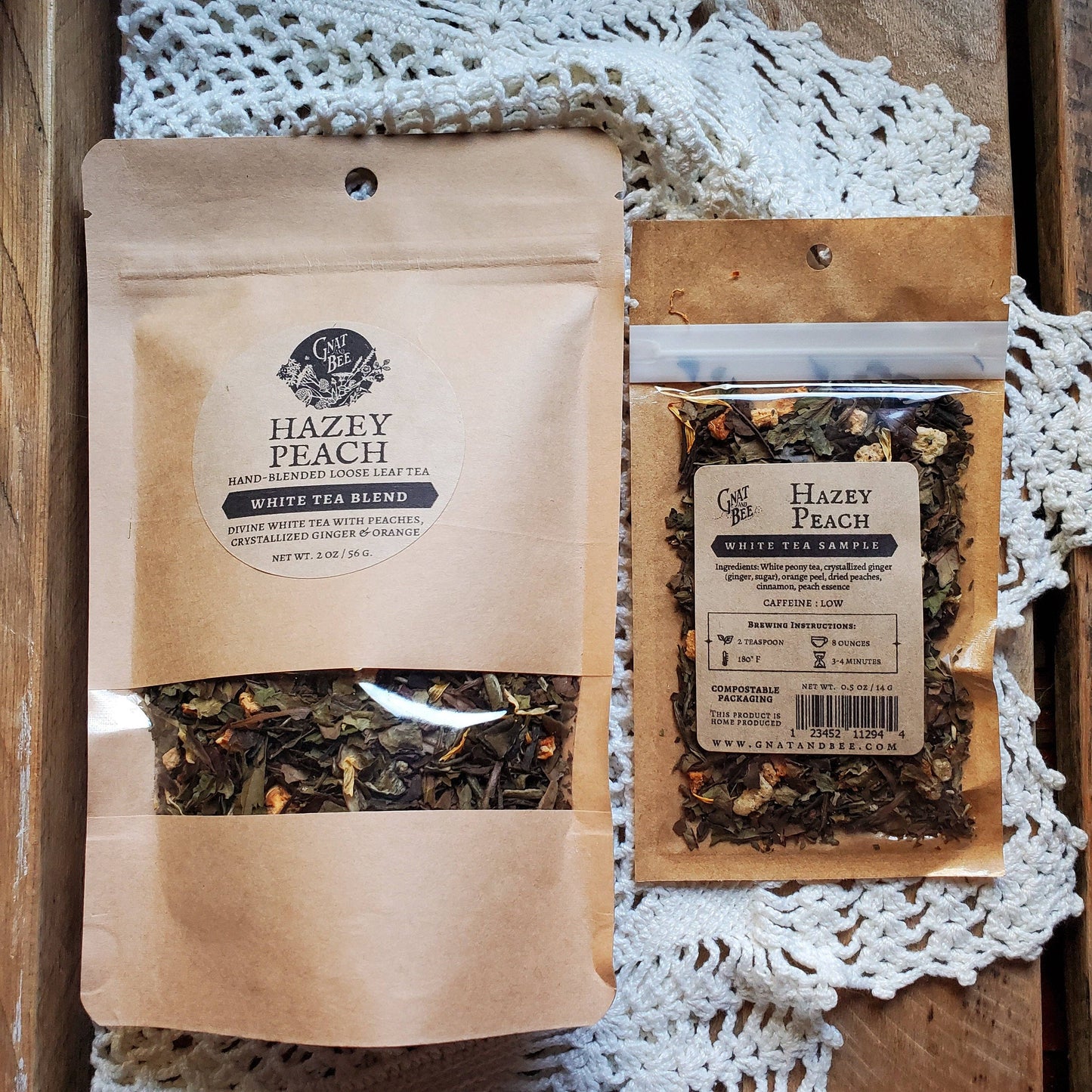 Two packages of 'Hazy Peach' white tea blend on a wooden surface with lace fabric.