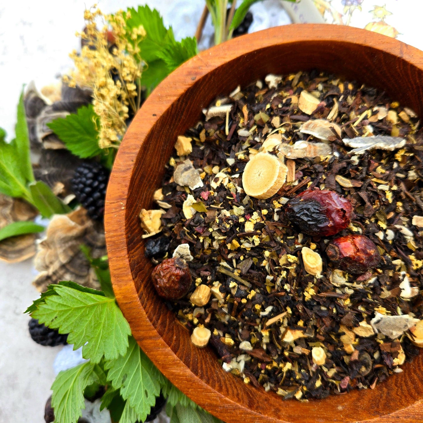 Wooden bowl filled with a mix of dried herbs and spices on a light background.