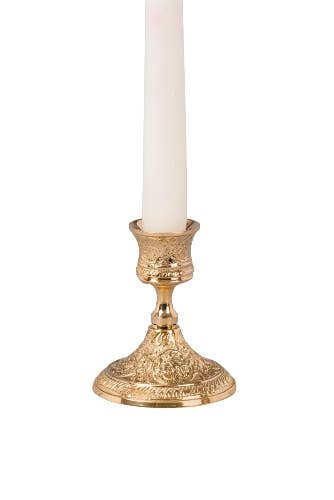 Gold candle holder with a white candle on a white background